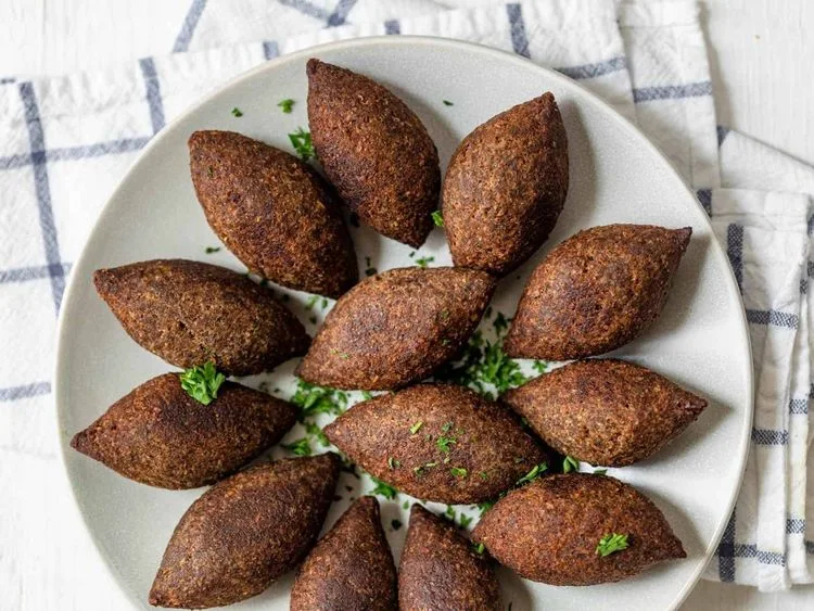 Fried kibbeh arranged around a bowl of dip