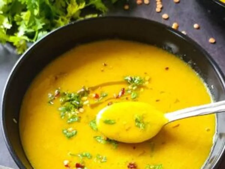 Golden lentil soup garnished with herbs