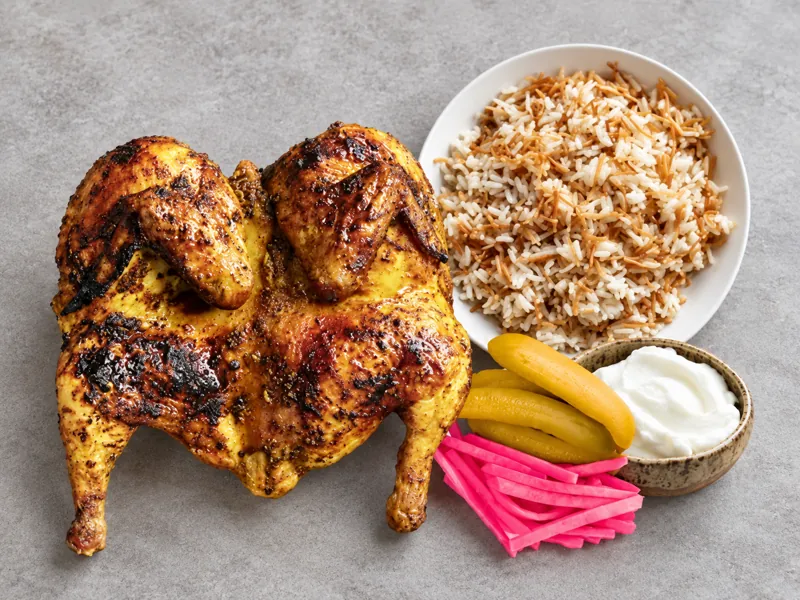 Grilled chicken served with a side of rice and pickles