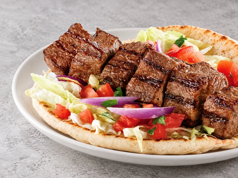 Beef skewers on flatbread with vegetables